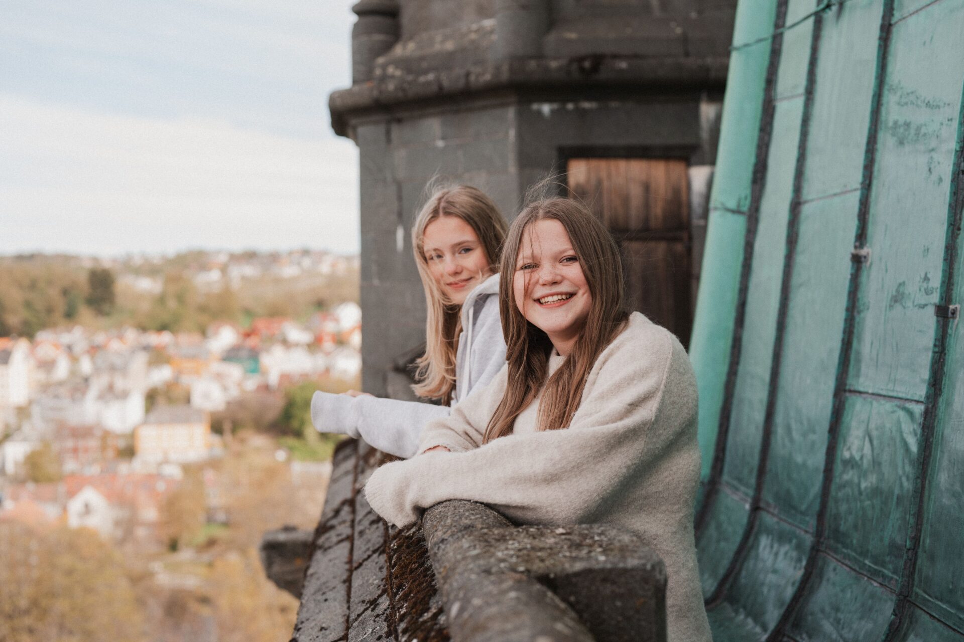 To unge jenter står og smiler og ser på utsikten fra tårnet i Nidarosdomen. To unge jenter står og smiler og ser på utsikten fra tårnet i Nidarosdomen.