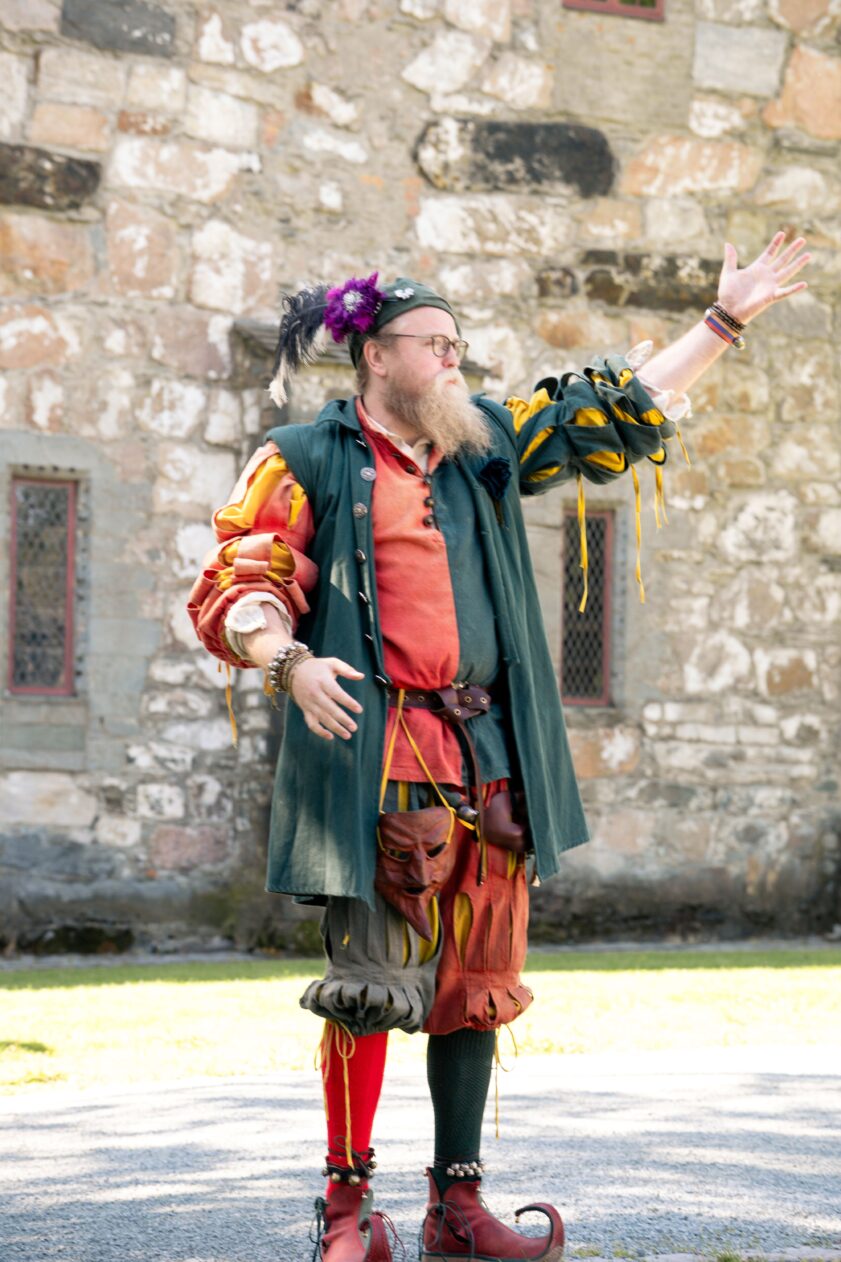En mann utkledd som gjøgler løfter hånden og vinker. En mann utkledd som gjøgler løfter hånden og vinker.